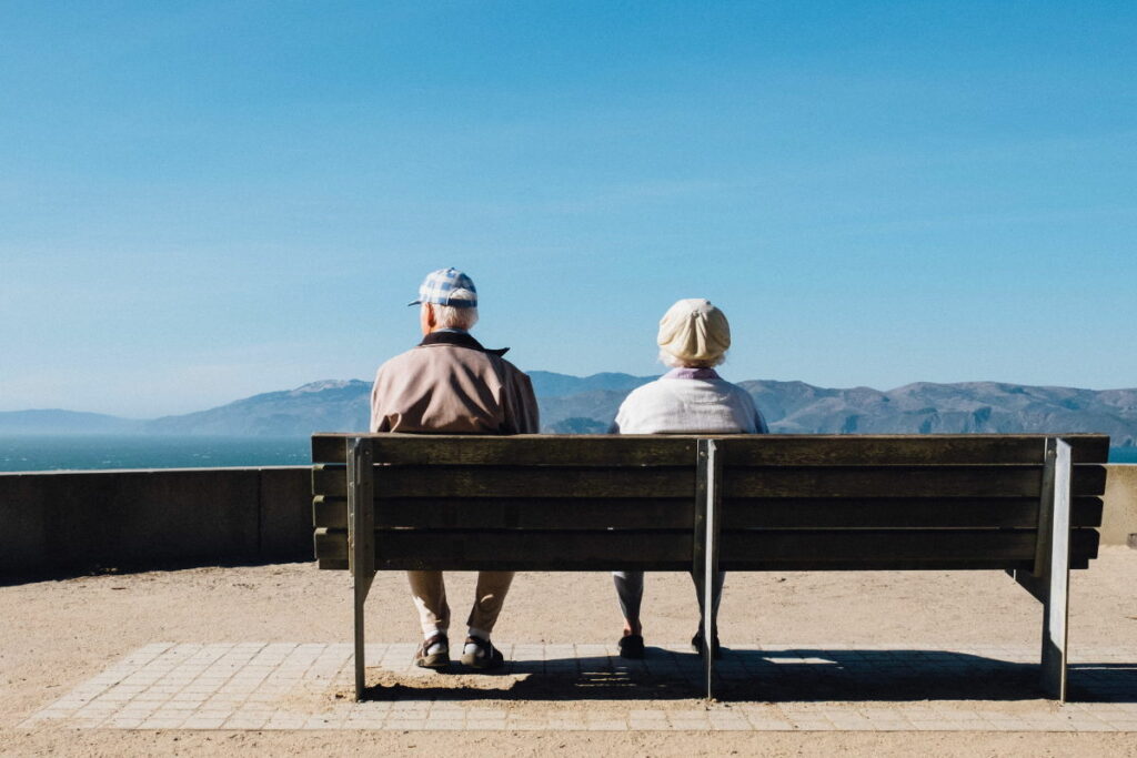 Pensión y Jubilación en Alemania - Información. Imagen ilustrativa: Dos abuelitos sentados en un banco mirando las montañas.